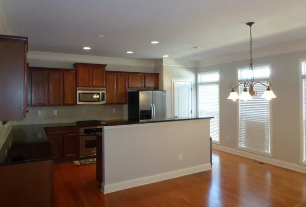 a kitchen with stainless steel appliances granite countertop a refrigerator a sink dishwasher a stove and white countertops with wooden floor