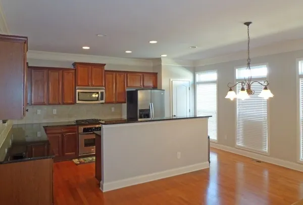 a kitchen with stainless steel appliances granite countertop a refrigerator a sink dishwasher a stove and white countertops with wooden floor