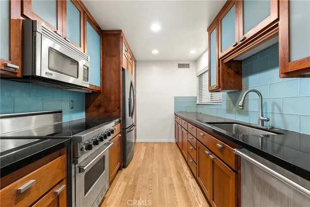 a kitchen with stainless steel appliances granite countertop a stove a sink and a microwave