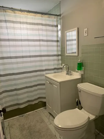 a bathroom with a sink a toilet a mirror and shower curtain