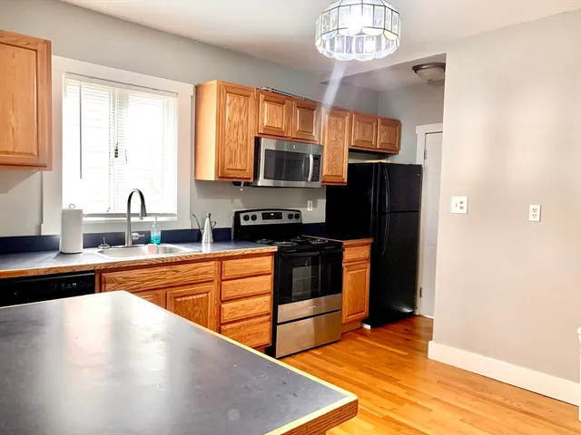 a kitchen with stainless steel appliances granite countertop a stove top oven a sink dishwasher a refrigerator and a microwave oven with wooden floor