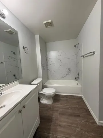a bathroom with a granite countertop sink a toilet and shower