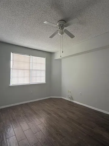an empty room with wooden floor fan and windows