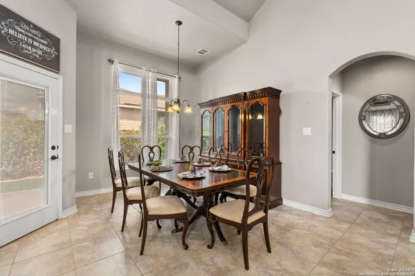 a view of a dining room and livingroom with furniture wooden floor a rug a painting and a chandelier