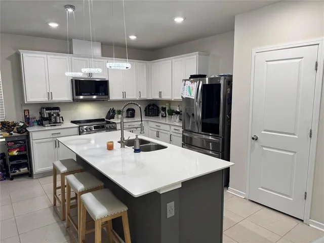 a kitchen with stainless steel appliances a refrigerator a sink a stove a table and chairs