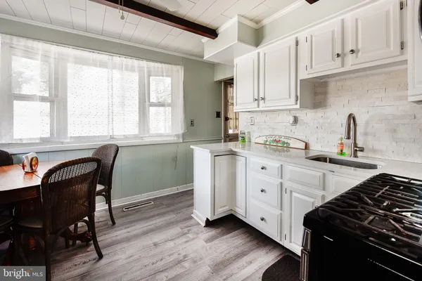 a kitchen with white cabinets and wooden floor