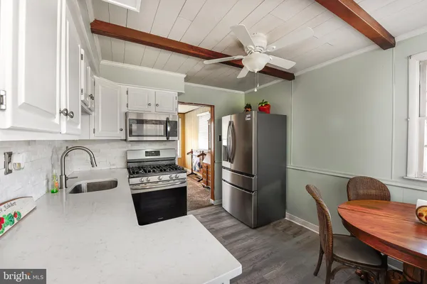 a kitchen with stainless steel appliances a refrigerator a sink a stove and white cabinets