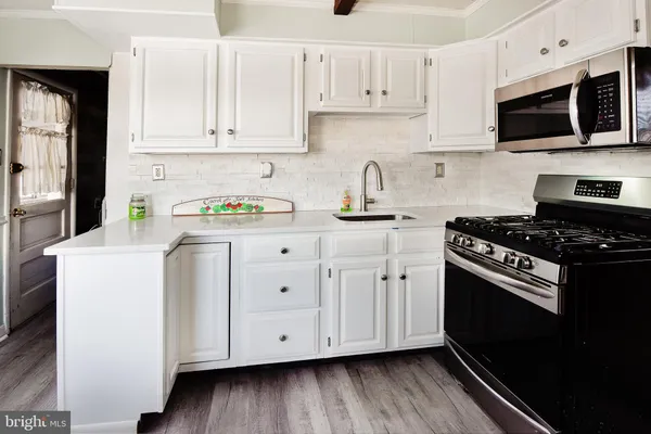 a kitchen with granite countertop a sink a stove and cabinets