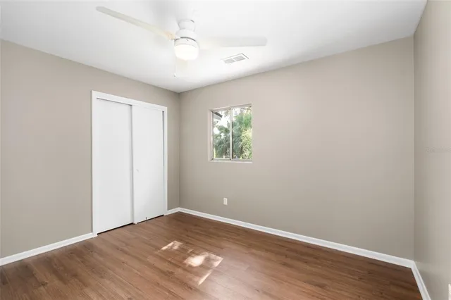 a view of empty room with wooden floor and fan