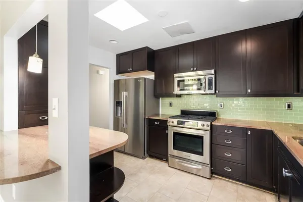 a kitchen with stainless steel appliances kitchen island granite countertop a refrigerator and a stove top oven