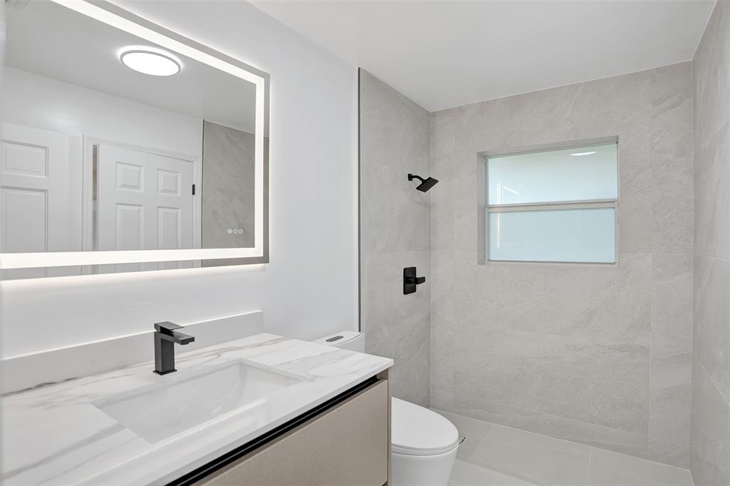 2891 Northwest 28th Terrace Boca Raton, FL 33434 - Photo 42 of 51 a bathroom with a sink vanity granite toilet and a mirror