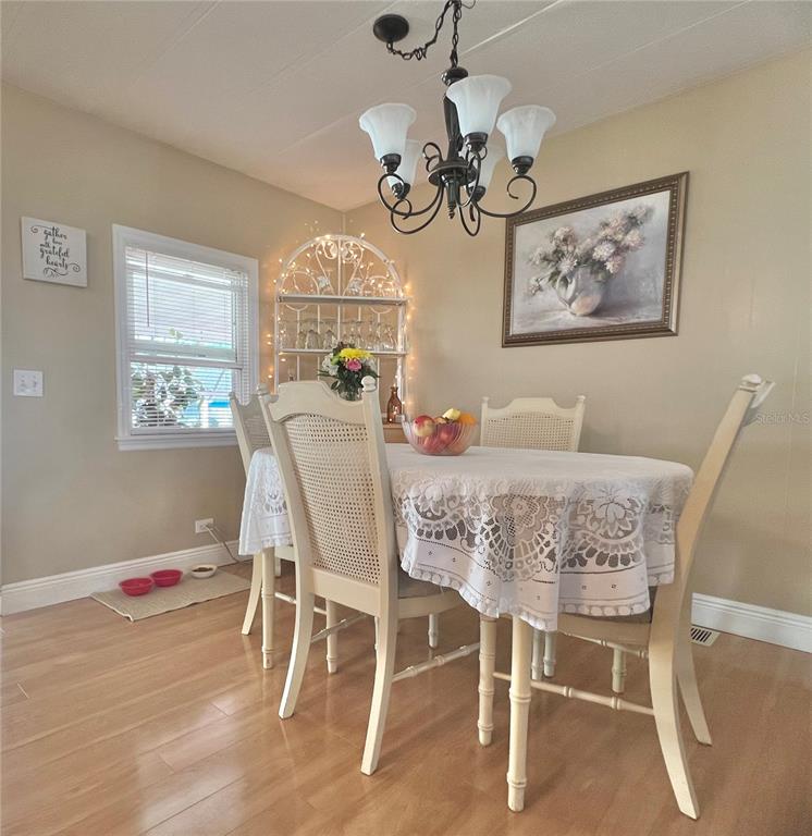 1100 South Belcher Road, Unit 113 Largo, FL 33771 - Photo 33 of 66 a dining room with wooden floor and chandelier
