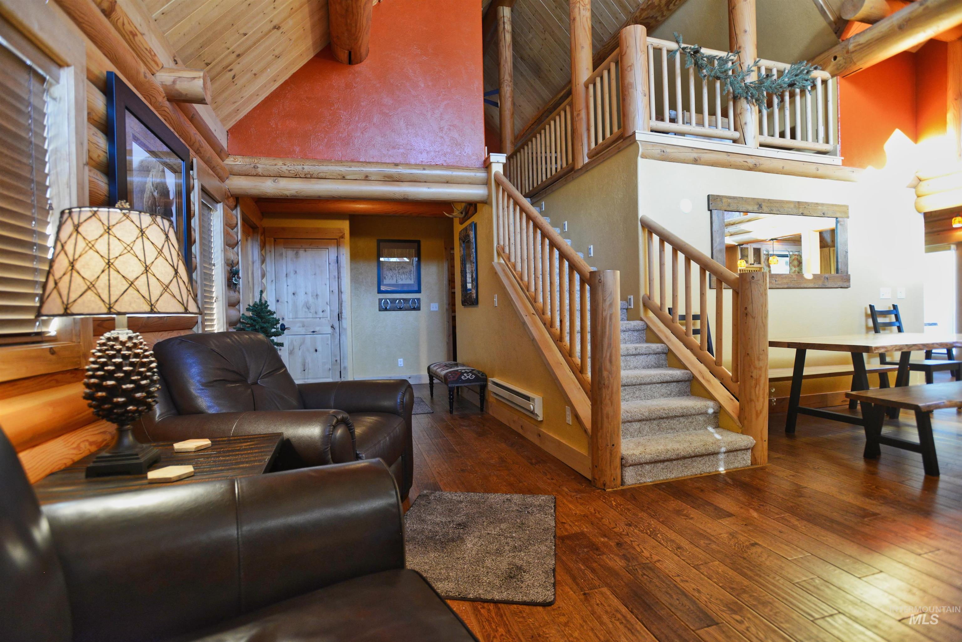 788 Chad Loop McCall, ID 83638 - Photo 5 of 22 Interior living space featuring wood-finish flooring, log beam construction, and a carpeted staircase with wood railings
