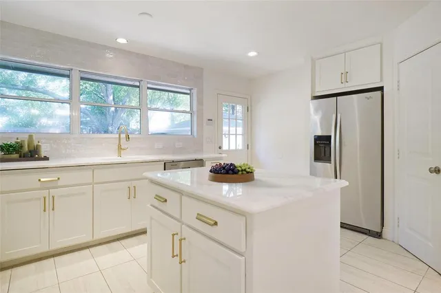 a kitchen with white cabinets and window