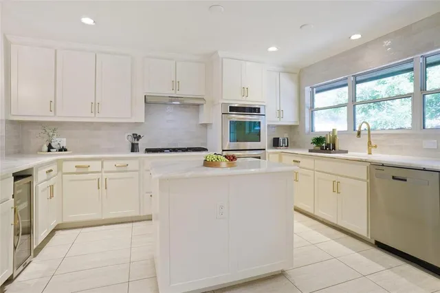 a kitchen with cabinets appliances a sink and a window
