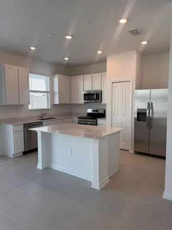 a kitchen with kitchen island a white cabinets and stainless steel appliances