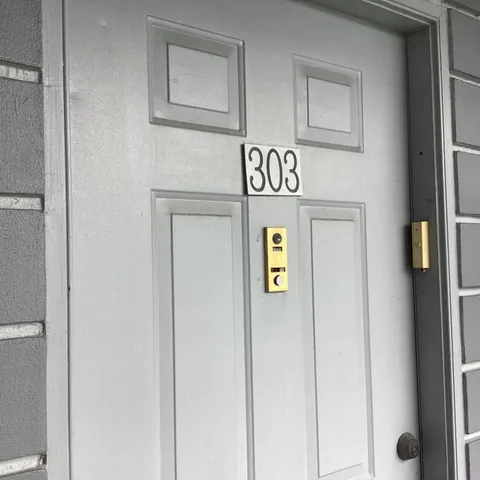 a view of a hallway with wooden floor and a bathroom