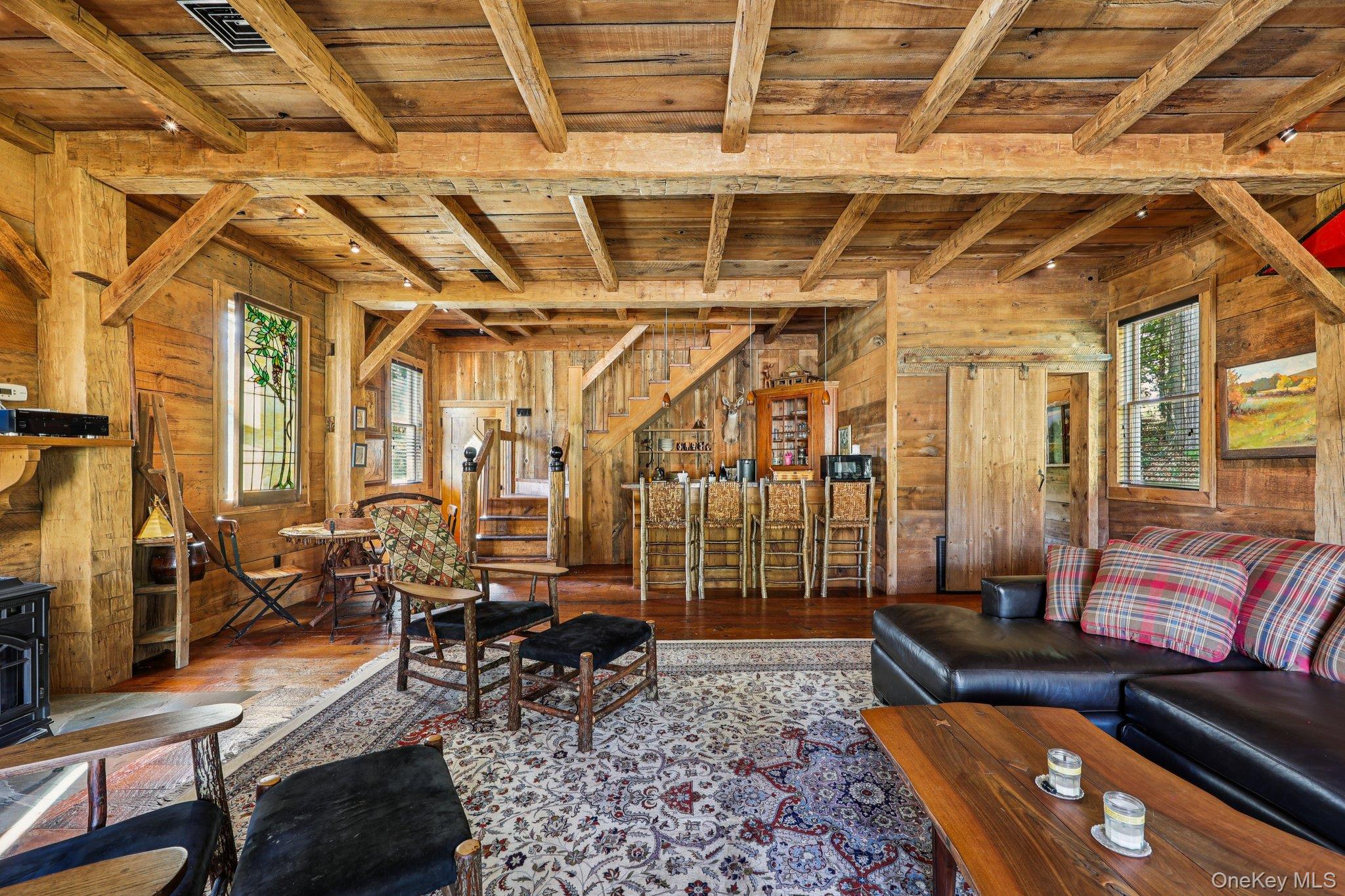 101 Upper Wisner Road Warwick, NY 10990 - Photo 22 of 48 Living area featuring a wooden ceiling with exposed beams, wood walls, healthy amount of natural light, a wood stove, and hardwood / wood-style floors