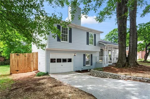 a view of a house with a yard and large tree