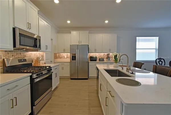a kitchen with kitchen island a sink stove top oven and refrigerator