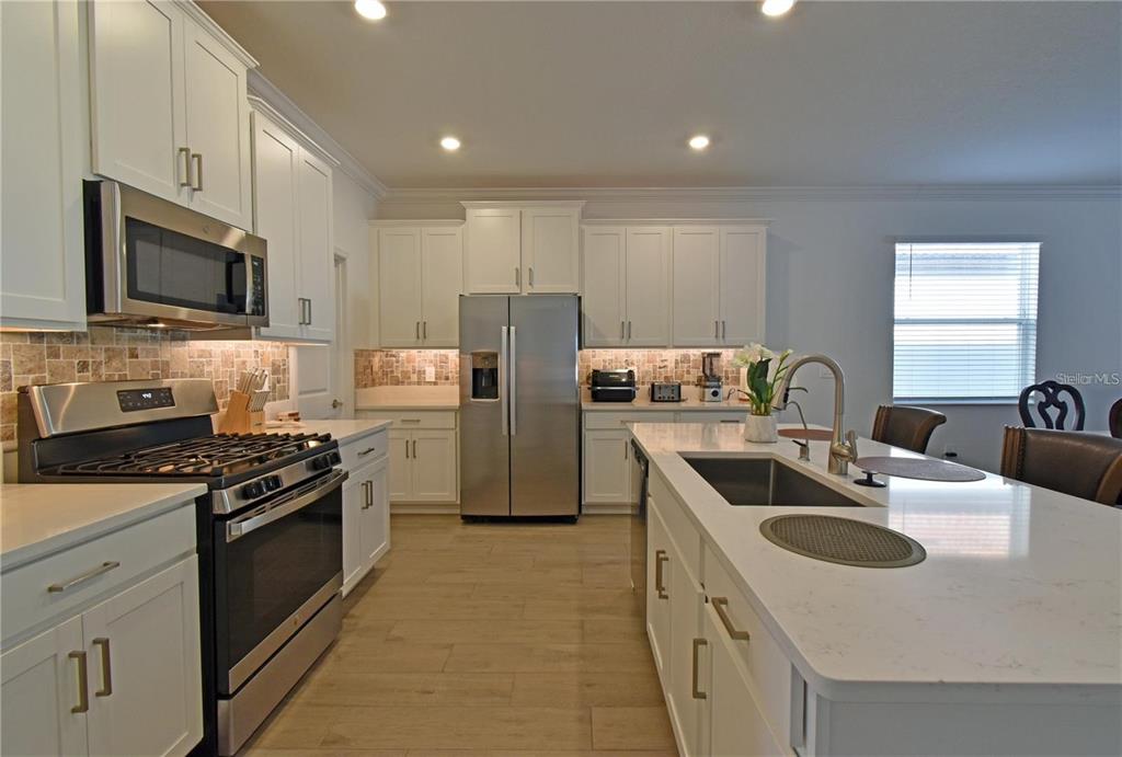 17304 Banded Gold Lane Wimauma, FL 33598 - Photo 12 of 44 a kitchen with kitchen island a sink stove top oven and refrigerator