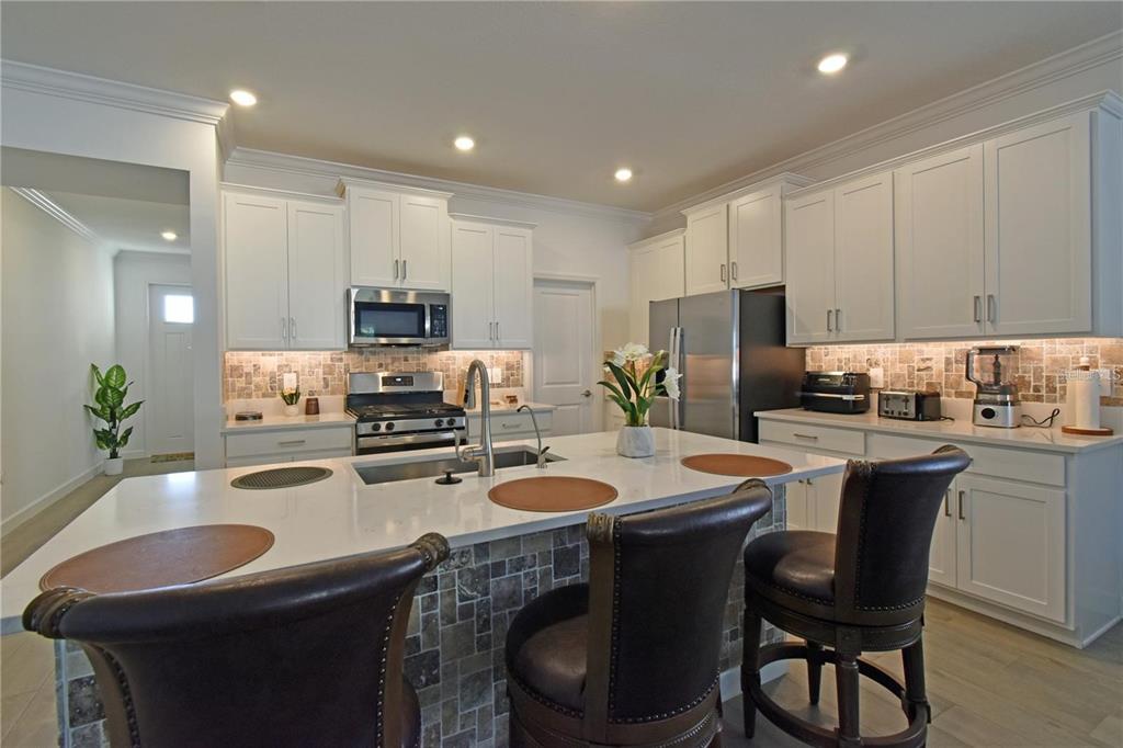 17304 Banded Gold Lane Wimauma, FL 33598 - Photo 14 of 44 a kitchen with a sink a microwave a stove and refrigerator