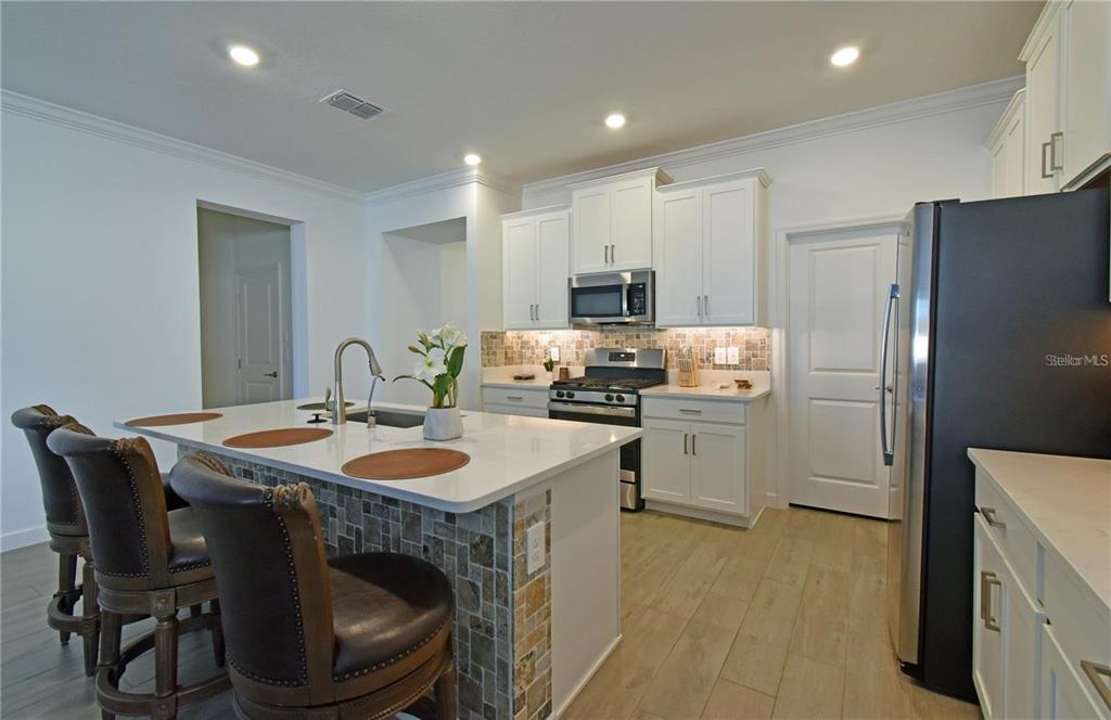 17304 Banded Gold Lane Wimauma, FL 33598 - Photo 16 of 44 a kitchen with a sink a stove a refrigerator a washer and dryer