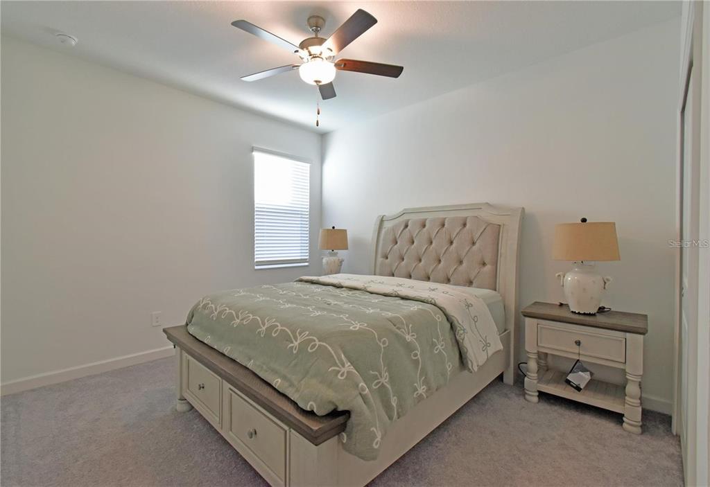17304 Banded Gold Lane Wimauma, FL 33598 - Photo 27 of 44 a spacious bedroom with a bed and a chandelier