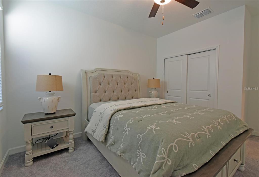 17304 Banded Gold Lane Wimauma, FL 33598 - Photo 28 of 44 a bedroom with a bed and a chandelier