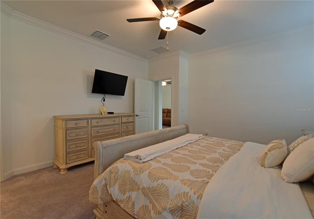 17304 Banded Gold Lane Wimauma, FL 33598 - Photo 36 of 44 a bedroom with a bed and a flat tv screen on dresser