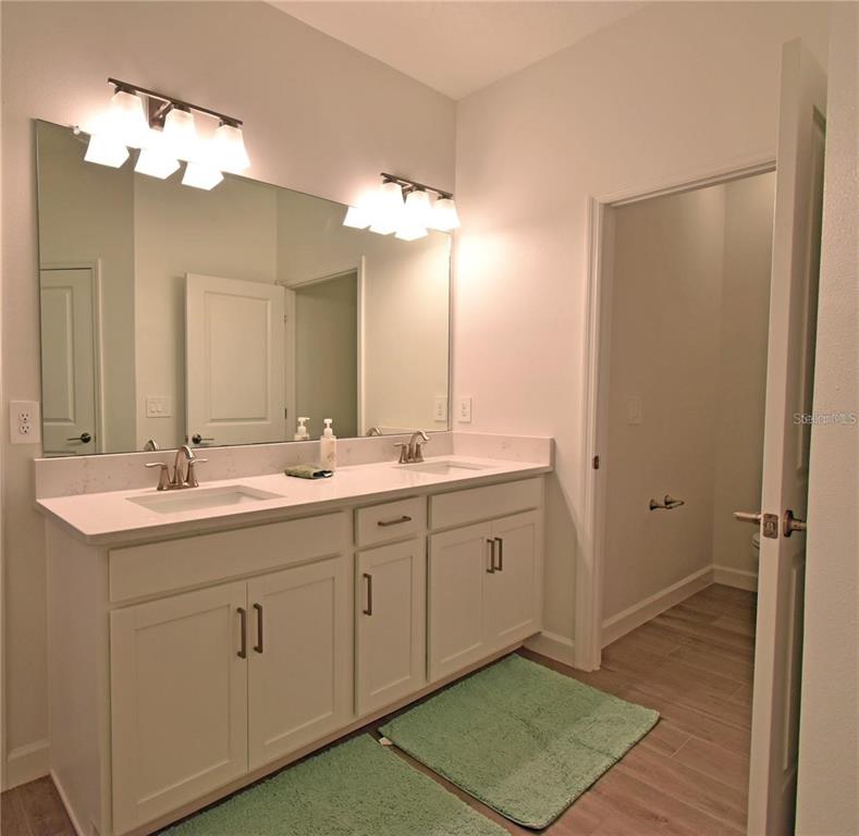 17304 Banded Gold Lane Wimauma, FL 33598 - Photo 39 of 44 a spacious bathroom with a double vanity sink a mirror and a shower