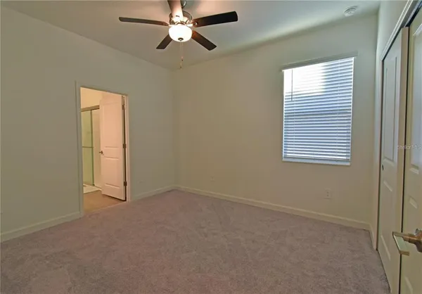 an empty room with a window and a chandelier fan