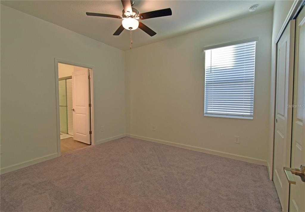 17304 Banded Gold Lane Wimauma, FL 33598 - Photo 44 of 44 an empty room with a window and a chandelier fan