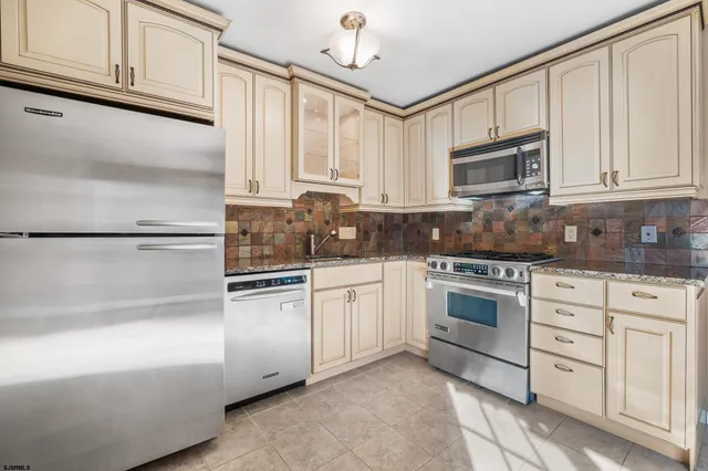 a kitchen with granite countertop white cabinets stainless steel appliances and a sink
