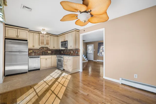 a kitchen with stainless steel appliances a refrigerator a sink dishwasher a stove and white countertops with wooden floor