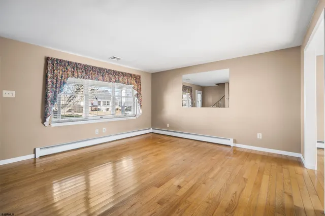 a view of an empty room with window and wooden floor