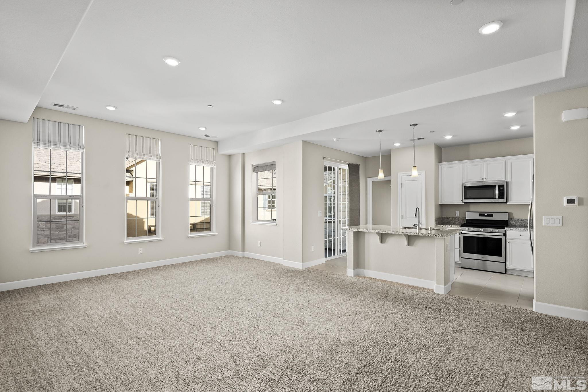 1855 Sea Horse Road, Unit A Reno, NV 89521 - Photo 4 of 32 a large white kitchen with stainless steel appliances kitchen island granite countertop a refrigerator oven a sink with granite countertops and cabinets