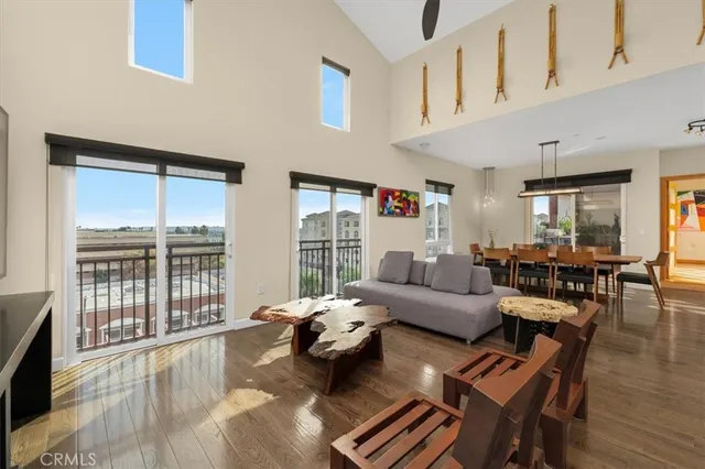 a living room with furniture large windows and wooden floor