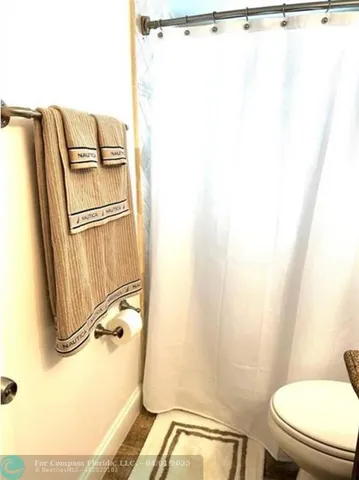 a bathroom with a granite countertop sink toilet a mirror and shower