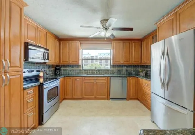a kitchen with stainless steel appliances granite countertop a refrigerator a stove a sink and a window