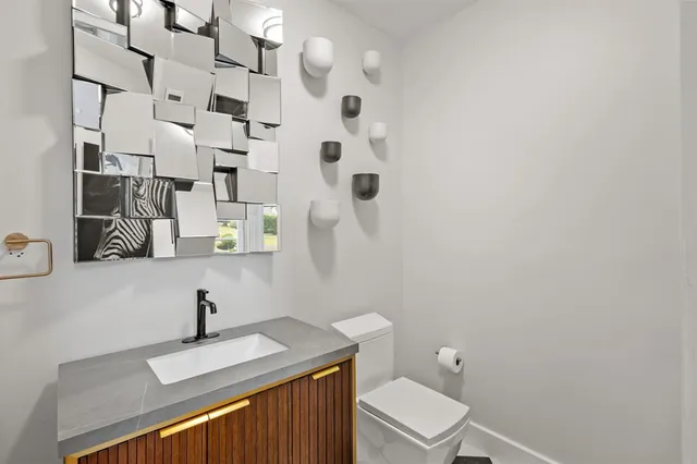 a bathroom with a granite countertop toilet sink and mirror