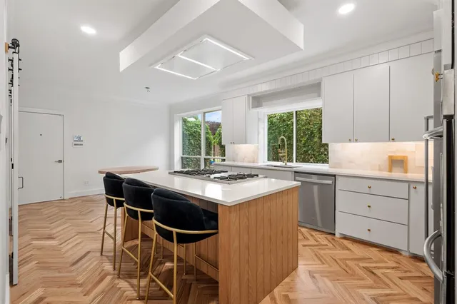 a kitchen with a stove windows and chairs
