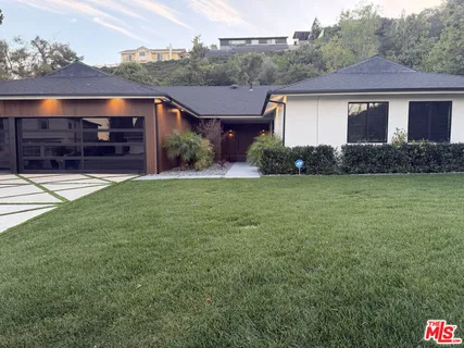 a front view of house with yard and trees in the background