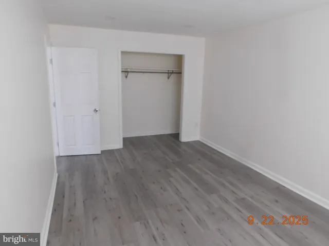a view of an empty room with wooden floor and closet