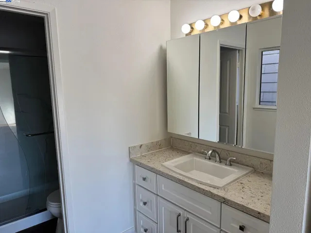 a bathroom with a granite countertop sink and a mirror