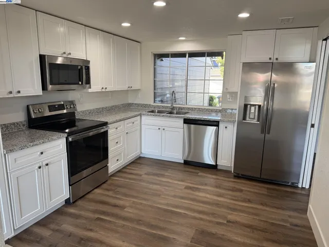 a kitchen with stainless steel appliances granite countertop a refrigerator a sink dishwasher a stove and a microwave oven on granite countertops