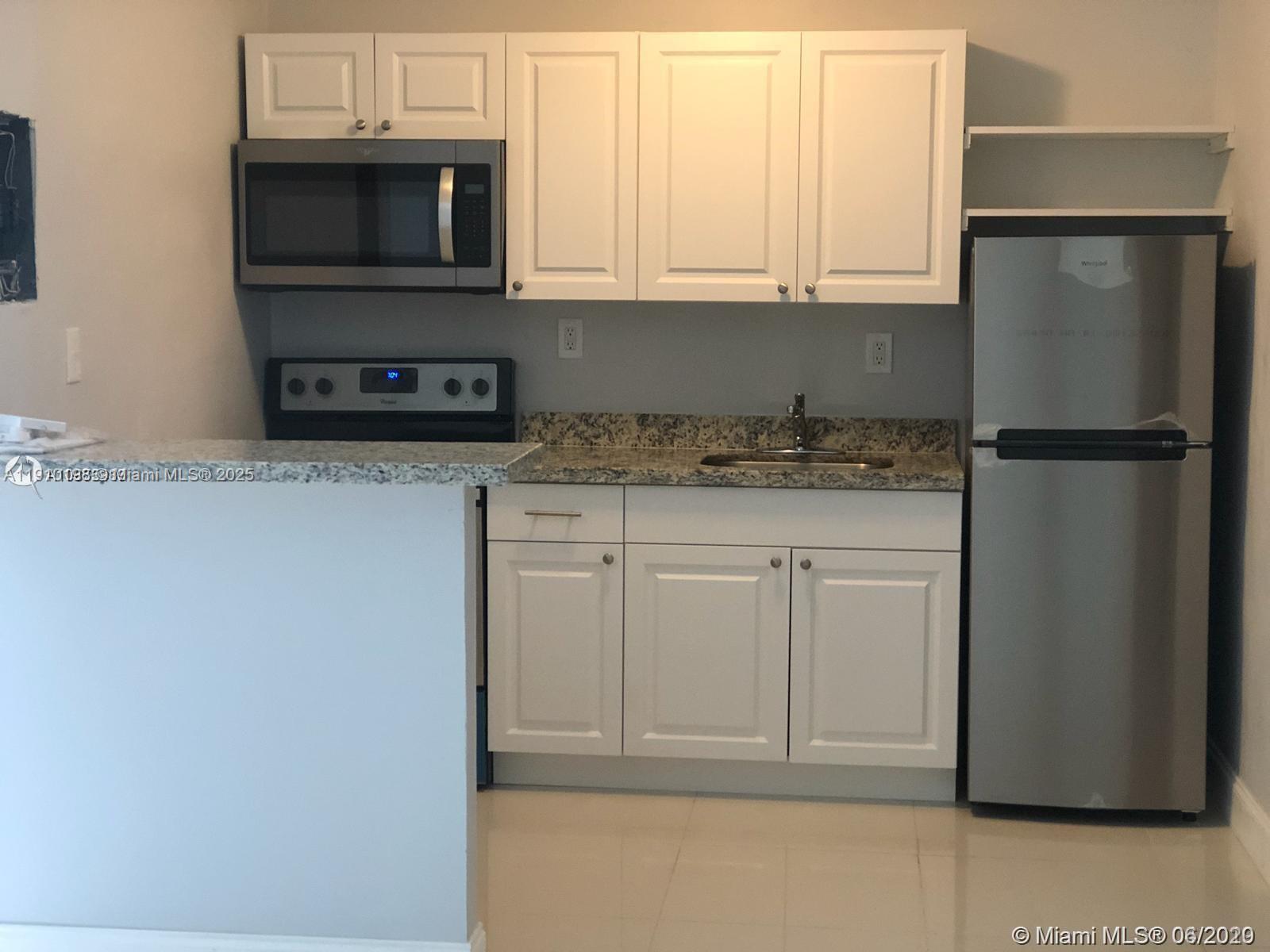 1479 Northwest 16th Street, Unit 2 Miami, FL 33125 - Photo 3 of 11 a kitchen with stainless steel appliances granite countertop a refrigerator a microwave a sink and white cabinets