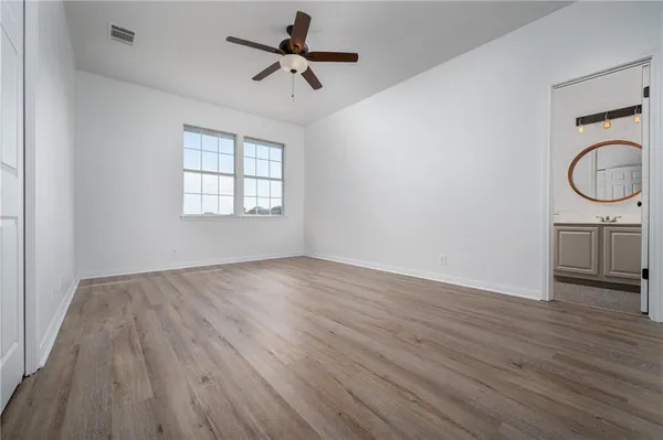 an empty room with wooden floor fan and windows