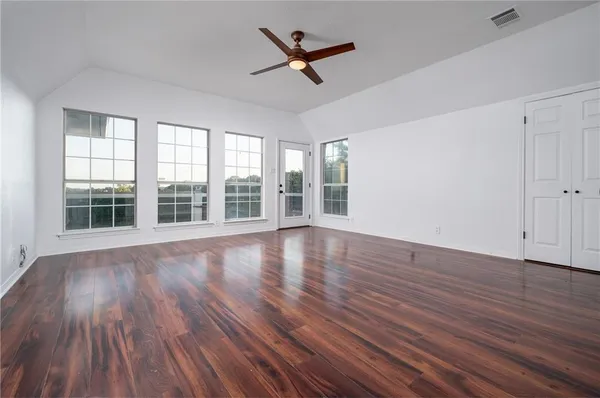 an empty room with wooden floor and windows