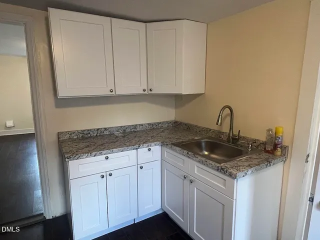 a kitchen with granite countertop white cabinets and a sink